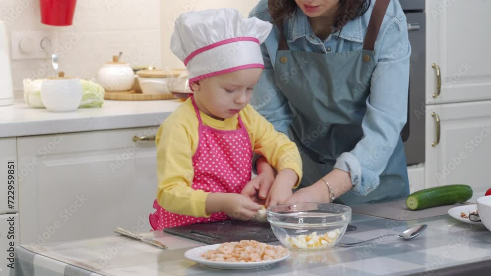 Mother with child preparing dinner together in modern kitchen at home, little boy helping mom cooking vegetable salad with shrimp. Mother with child preparing dinner together in modern kitchen at home, little boy helping mom cooking vegetable salad with shrimp.