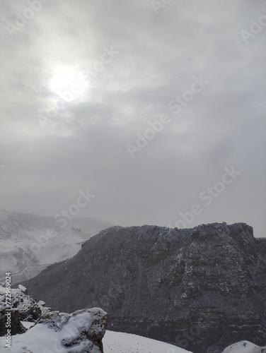 snow covered mountains with foggy sky, snowing