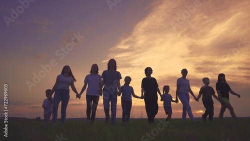 large friendly community family silhouette walk in the park. friendly family holding hands walking in nature in the park. happy family kid concept. silhouette large group people dream holding hands