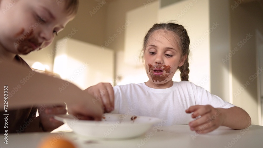 Obraz premium baby boy and girl eat chocolate. dirty little baby kids in the kitchen eating chocolate in the morning. happy family eating sweets kid dream concept. baby dirty sweet face eating chocolate cocoa