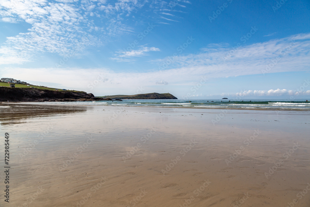 Looking out over the sandy beach at Polzeath in Cornwall, with a blue sky overhead