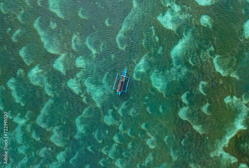 vista cenital de barco pesquero con fondo de mar turquesa en indonesia photo
