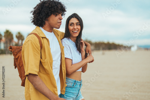 Young couple spending time together at the beach, celebrating success. Young happy couple on seashore in the lights of sunset. Shot of a young couple going for a romantic walk on the beach