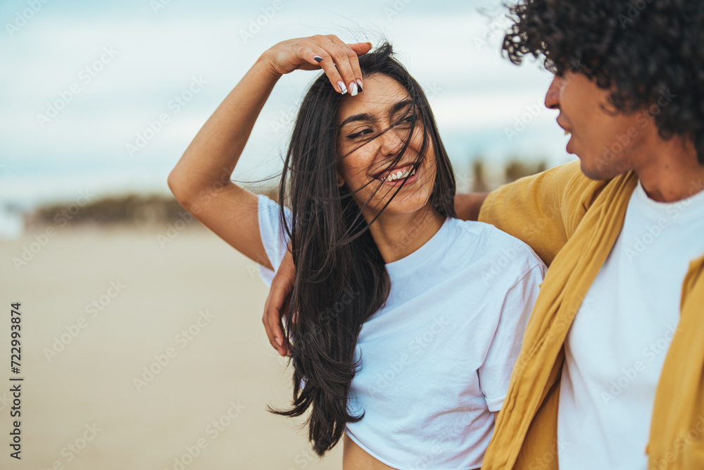 Couple walking on beach. Young happy interracial couple walking on beach smiling holding around each other. Lovely couple walking on beach. Space for text. Couple walking on beach. Young happy interracial couple walking on beach smiling holding around each other. Lovely couple walking on beach. Space for text.