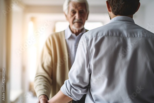 Senior man holding hands with his adult son in nursing home. Elderly people and healthcare concept.