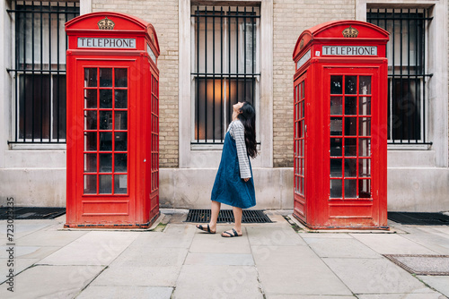 Young woman looking up while standing between telephone booth photo