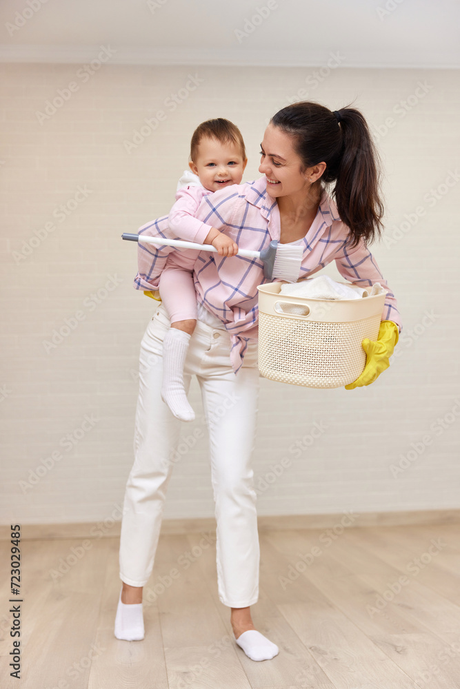 happy mother housewife is holding cute baby girl and basket with laundry , Happy family happy mother housewife is holding cute baby girl and basket with laundry , Happy family