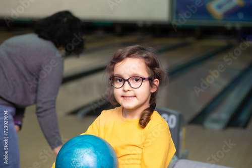 Cute little kid girl with ball at bowling club