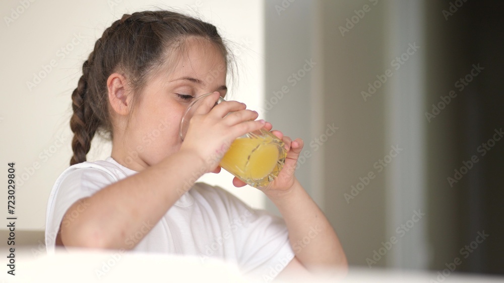 girl child drinking juice. happy family a healthy indoors eating kid dream concept. daughter girl drinking yellow juice from a glass cup in the kitchen. child drinking fruit juice girl child drinking juice. happy family a healthy indoors eating kid dream concept. daughter girl drinking yellow juice from a glass cup in the kitchen. child drinking fruit juice