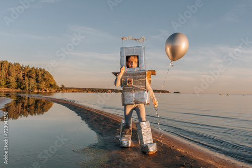 Boy in astronaut suit holding silver balloon at beach photo