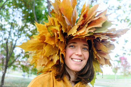 Smiling woman wearing wreath made of autumn leaves in park photo