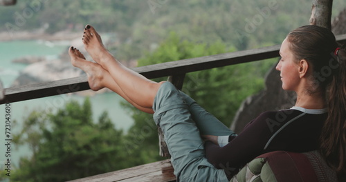 Woman relax sitting on balcony enjoy rock sea view. Tourist girl outdoor lifestyle travel on summer holiday vacation. Meditation, outdoor relaxation concept. Side view