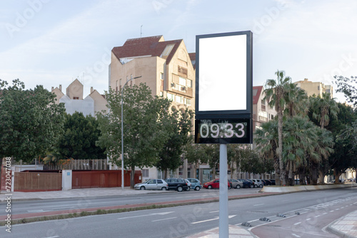Urban digital clock post with a blank advertising panel against a cityscape, ideal for promotions. Vertical billboard mockup, empty display. Copy space for text, picture. photo