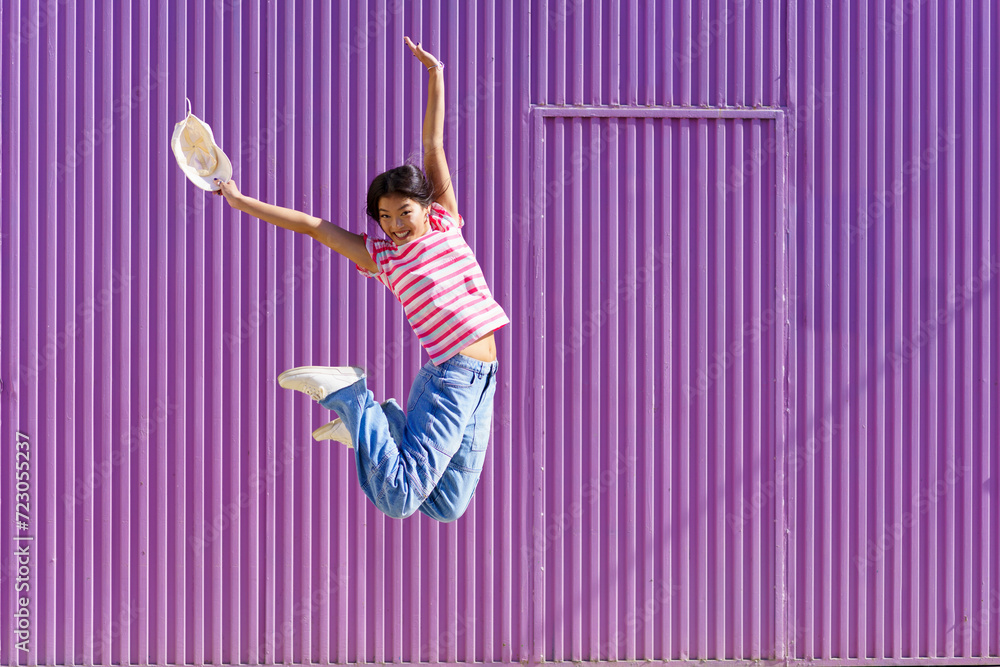 Cheerful woman jumping in front of purple background Cheerful woman jumping in front of purple background