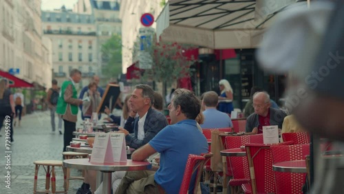 Parisians sitting at the tables of a street cafe in Paris