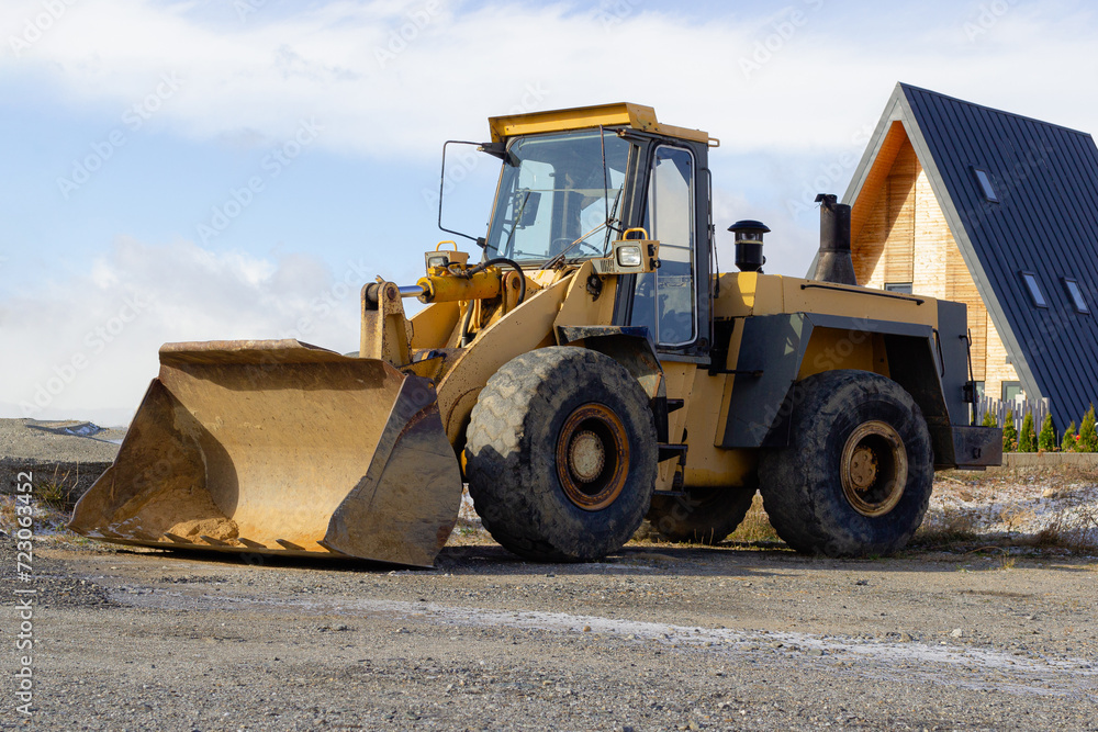 Large wheel loader on the road for construction against a blue sky. Snow clearing on city roads in winter. Snow removal excavator after snow falls and blizzards. Building and construction site Large wheel loader on the road for construction against a blue sky. Snow clearing on city roads in winter. Snow removal excavator after snow falls and blizzards. Building and construction site