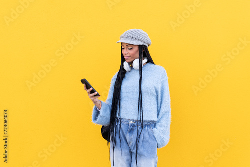 Woman using smart phone in front of yellow wall photo