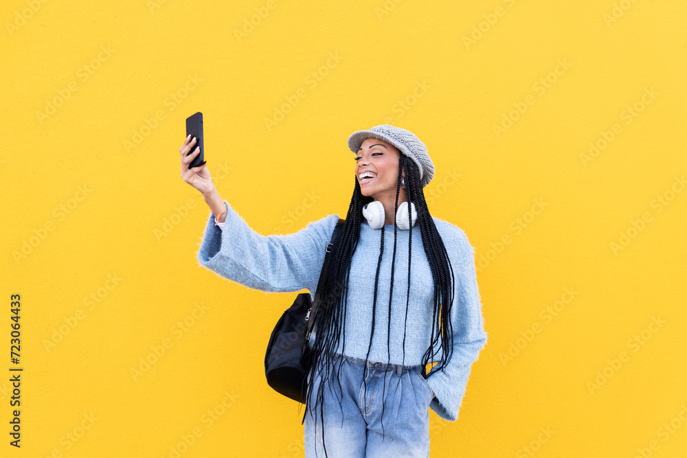 Cheerful woman taking selfie in front of yellow wall Cheerful woman taking selfie in front of yellow wall