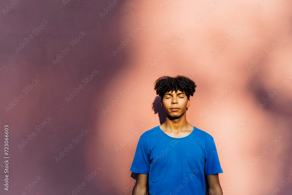 Man with eyes closed standing in front of wall Man with eyes closed standing in front of wall
