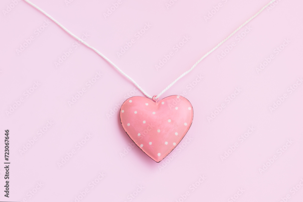 Steel pink heart hanging on a white rope on pink background, Vintage Pink heart shape