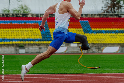 male runner sprinter on prosthesis running stadium track, disabled athlete para athletics competition