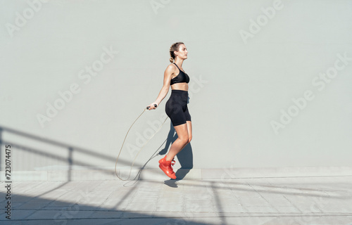 Young athlete skipping rope on sunny day photo