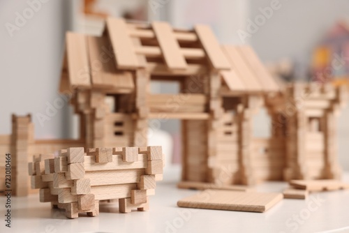 Wooden entry gate and building blocks on white table indoors  selective focus. Children s toy