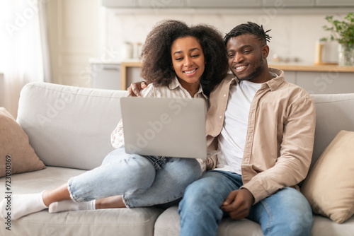 Young Black Spouses Using Laptop Together Browsing Internet At Home