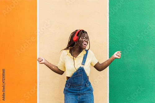 Happy young woman dancing in front of multi colored wall photo