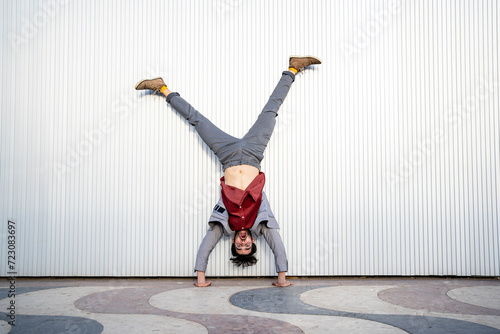 Businessman doing handstand on footpath in front of wall photo