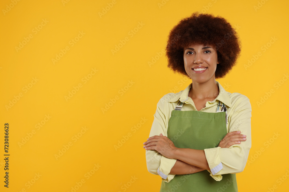 Portrait of happy young woman in apron on orange background. Space for text Portrait of happy young woman in apron on orange background. Space for text