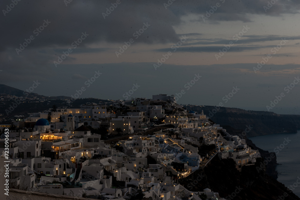 View of Firostefani village in Santorini at sunset with blue dome church and night sky