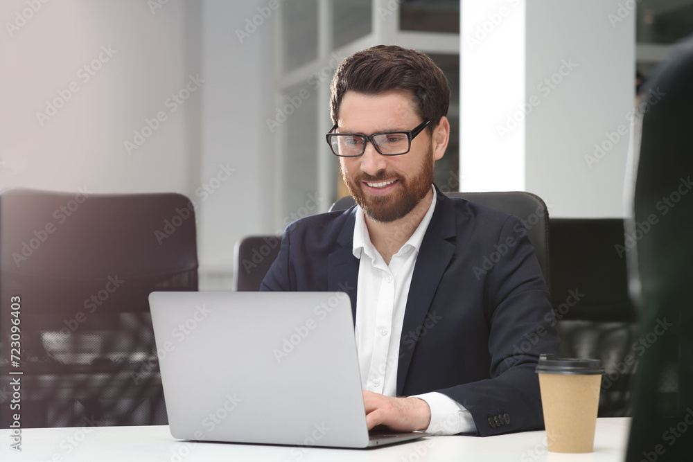 Man working on laptop at white desk in office Man working on laptop at white desk in office