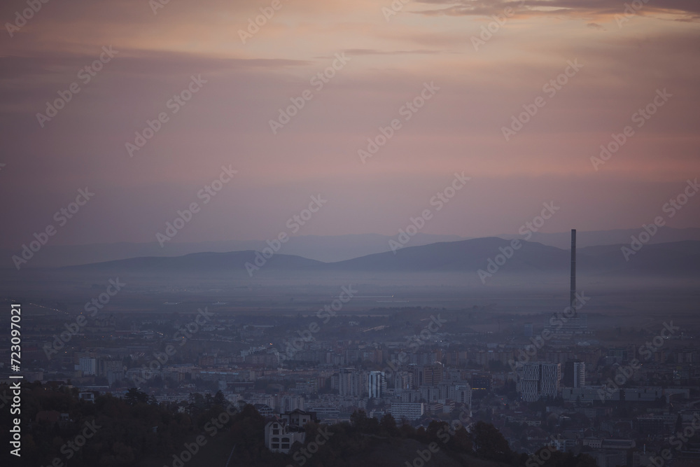 Cityscape in morning light and morning fog. Stunning, soft view of purple blue hour sky above scenic cityscape covered by haze and mist. 