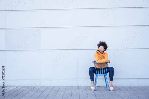 Thoughtful woman sitting on chair in front of wall