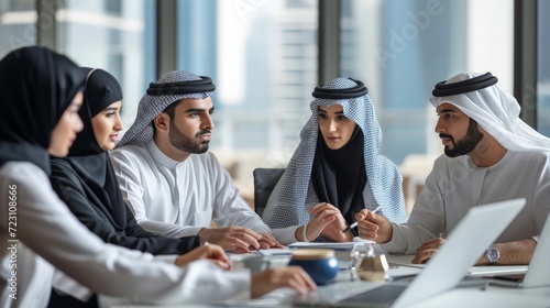 Group of middle-eastern corporate business people wearing traditional emirati clothes meeting in the office in Dubai - Business team working and brainstorming in the UAE photo
