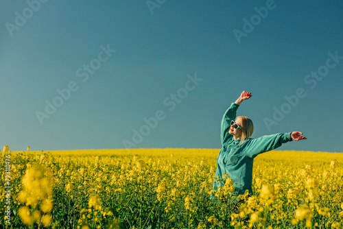 Carefree woman with arms raised standing in rapeseed field photo