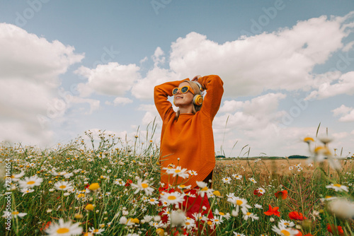 Woman with head in hands standing amidts flowers in chamomile field photo