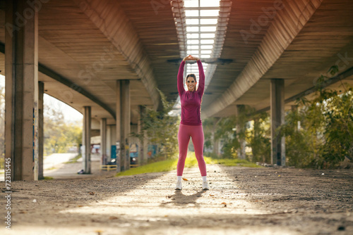 A fit sportswoman is stretching and warming up in urban exterior. © dusanpetkovic1