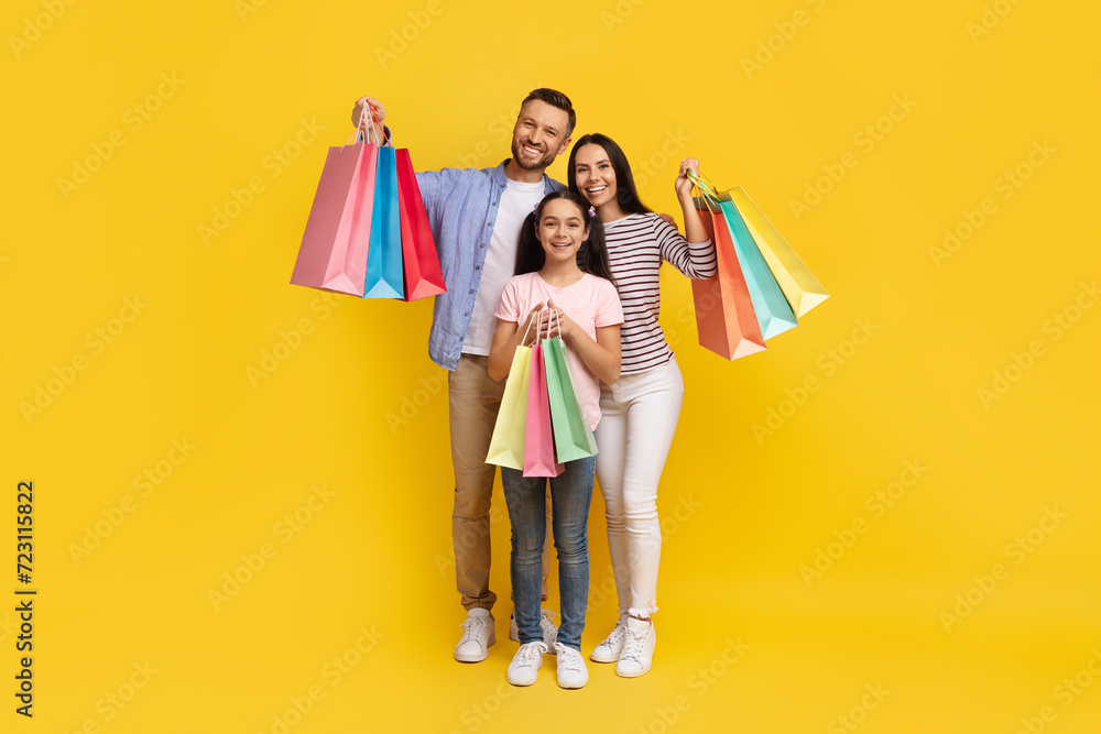 Sales Concept. Happy caucasian family of three holding shopping bags and smiling Sales Concept. Happy caucasian family of three holding shopping bags and smiling