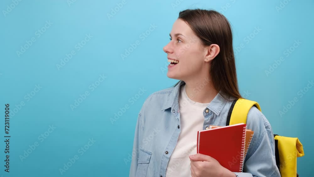 Portrait of excited young woman student in shirt with backpack hold notebooks keeping mouth open looking aside, isolated on blue studio background. Education in high school university college concept Portrait of excited young woman student in shirt with backpack hold notebooks keeping mouth open looking aside, isolated on blue studio background. Education in high school university college concept
