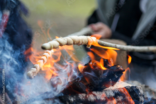 Bread, twisted on a skewer, baked on fire. Stockbrot. Barbecue food, open fire. The children prepare a roast meal. Children's summer camp. photo