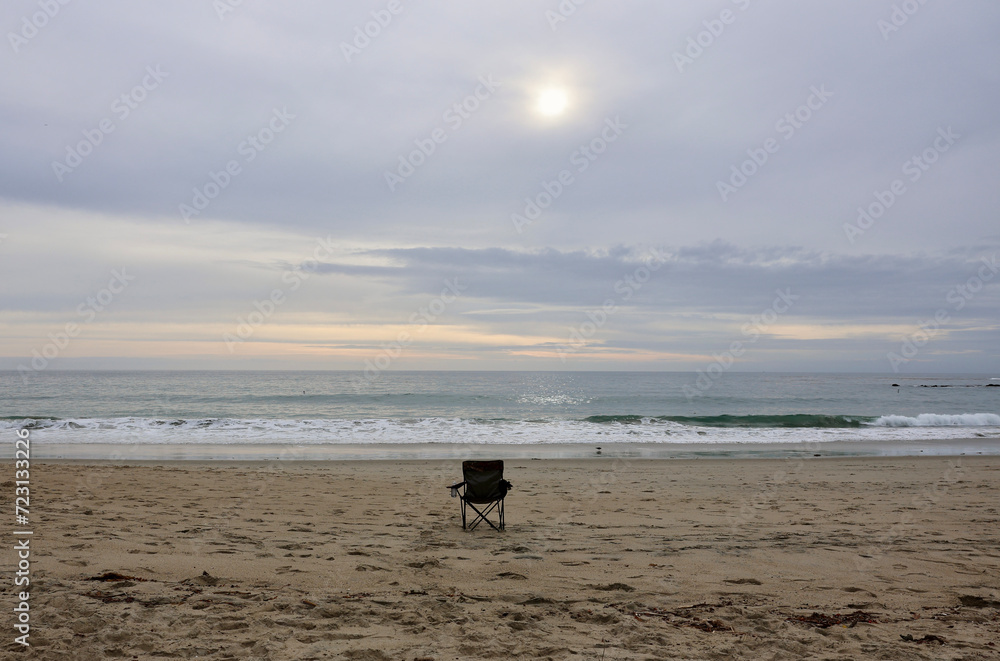 single chair on an empty beach late in afternoon single chair on an empty beach late in afternoon