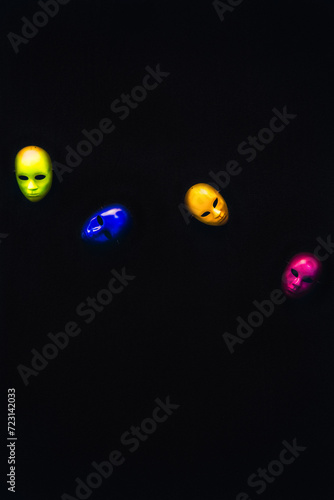 Different colorful carnival masks scattered on a black background.