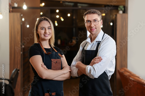 Portrait of professional hairdressers wearing aprons in beauty salon