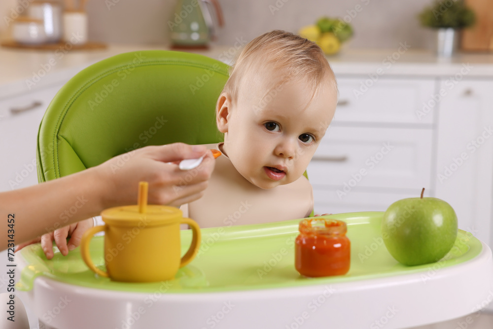 Mother feeding her cute little baby with healthy food at home Mother feeding her cute little baby with healthy food at home