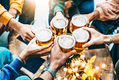 Group of friends drinking and toasting beer at brewery bar restaurant - Friendship concept with people enjoying happy hour sitting at bar table  - Close up image of brew glasses