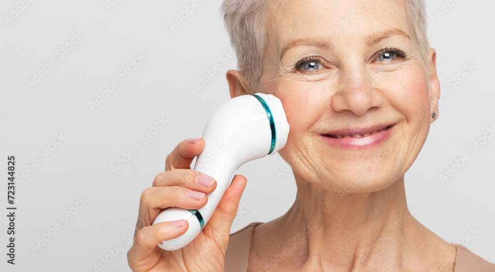 pretty senior woman with short hair using facial massager for perfect fresh skin pretty senior woman with short hair using facial massager for perfect fresh skin