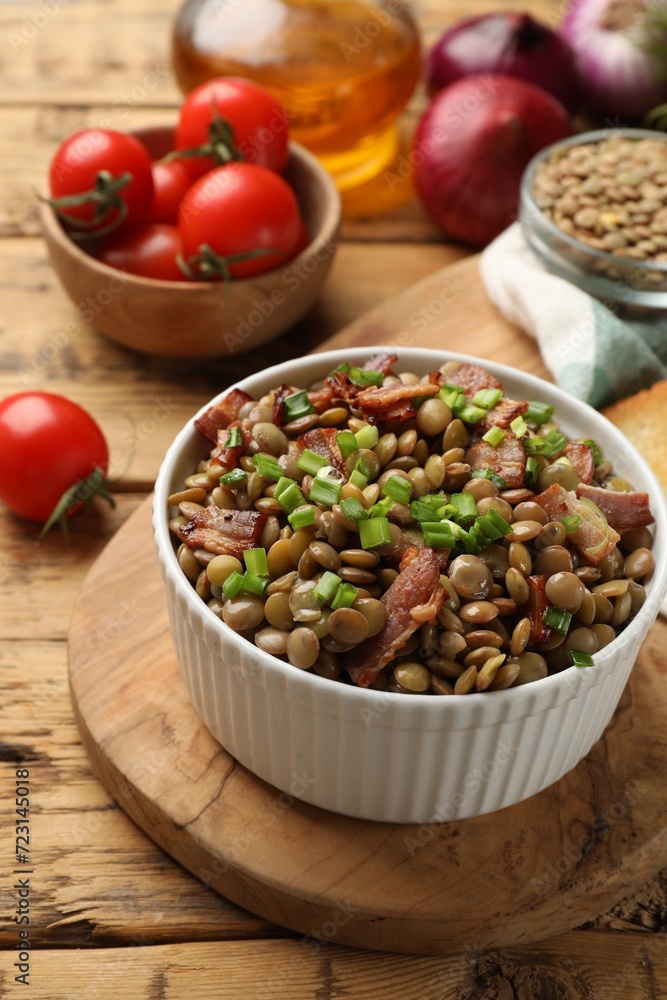Delicious lentils with bacon and green onion in bowl served on wooden table Delicious lentils with bacon and green onion in bowl served on wooden table