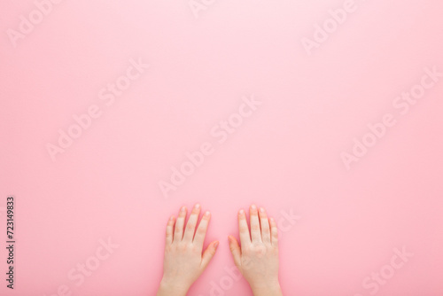 Little girl hands on light pink table background. Pastel color. Closeup. Point of view shot. Empty place for text. Top down view.